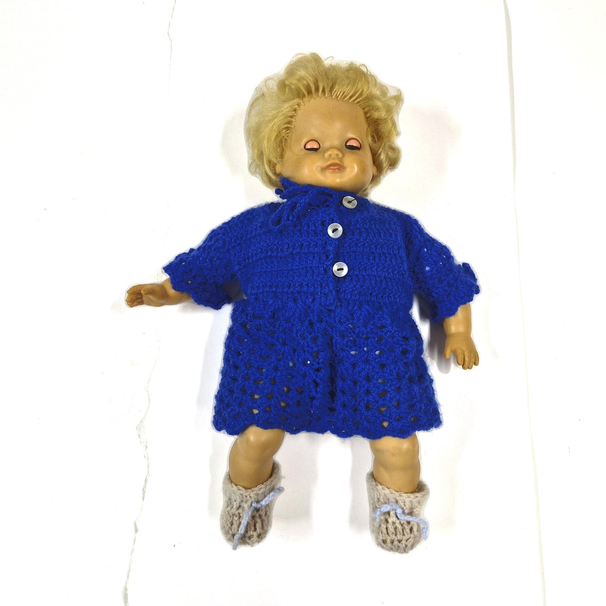 Vintage babypop met slaapogen, blond haar en gehaakt blauw pakje