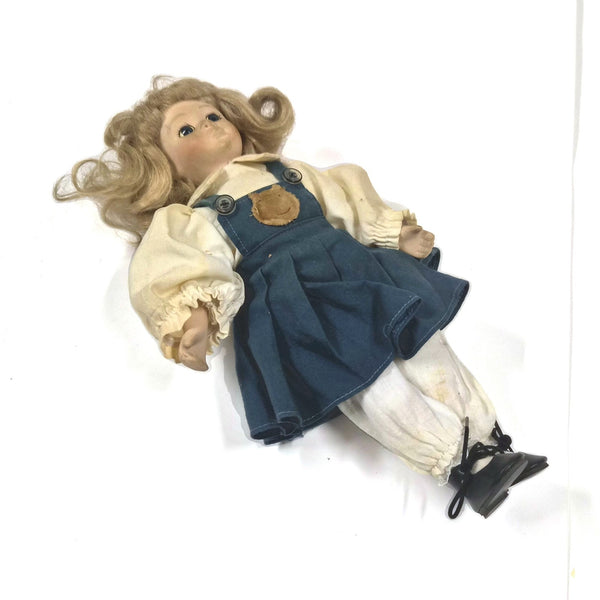 Vintage porseleinen pop met blond krullend haar en blauwe jurk