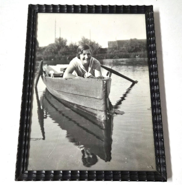 Vintage ingelijste zwart-witfoto van lachende vrouw in roeiboot, houten lijst